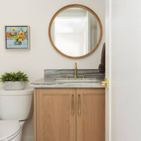 Thumbnail of http://Simple%20powder%20bathroom%20design%20with%20a%20vanity%20and%20toilet%20next%20to%20each%20other%20on%20the%20wall.%20Above%20the%20vanity%20is%20a%20round%20mirror%20and%20modern,%20horizontal%20light%20fixture.