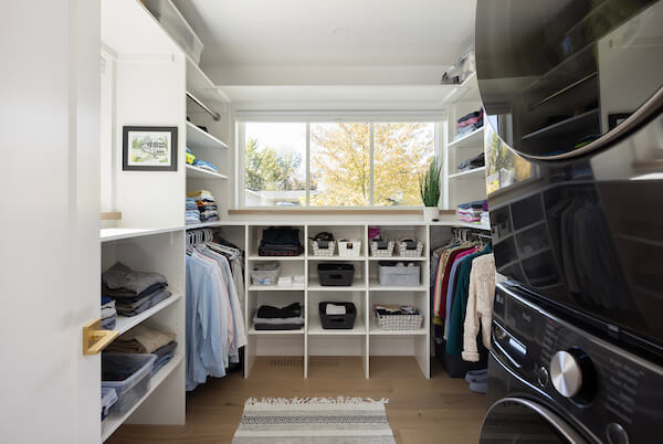 Primary closet with lots of storage and a stacked washer and dryer.