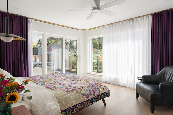 Primary bedroom design with lots of natural light and curtains all the way around.