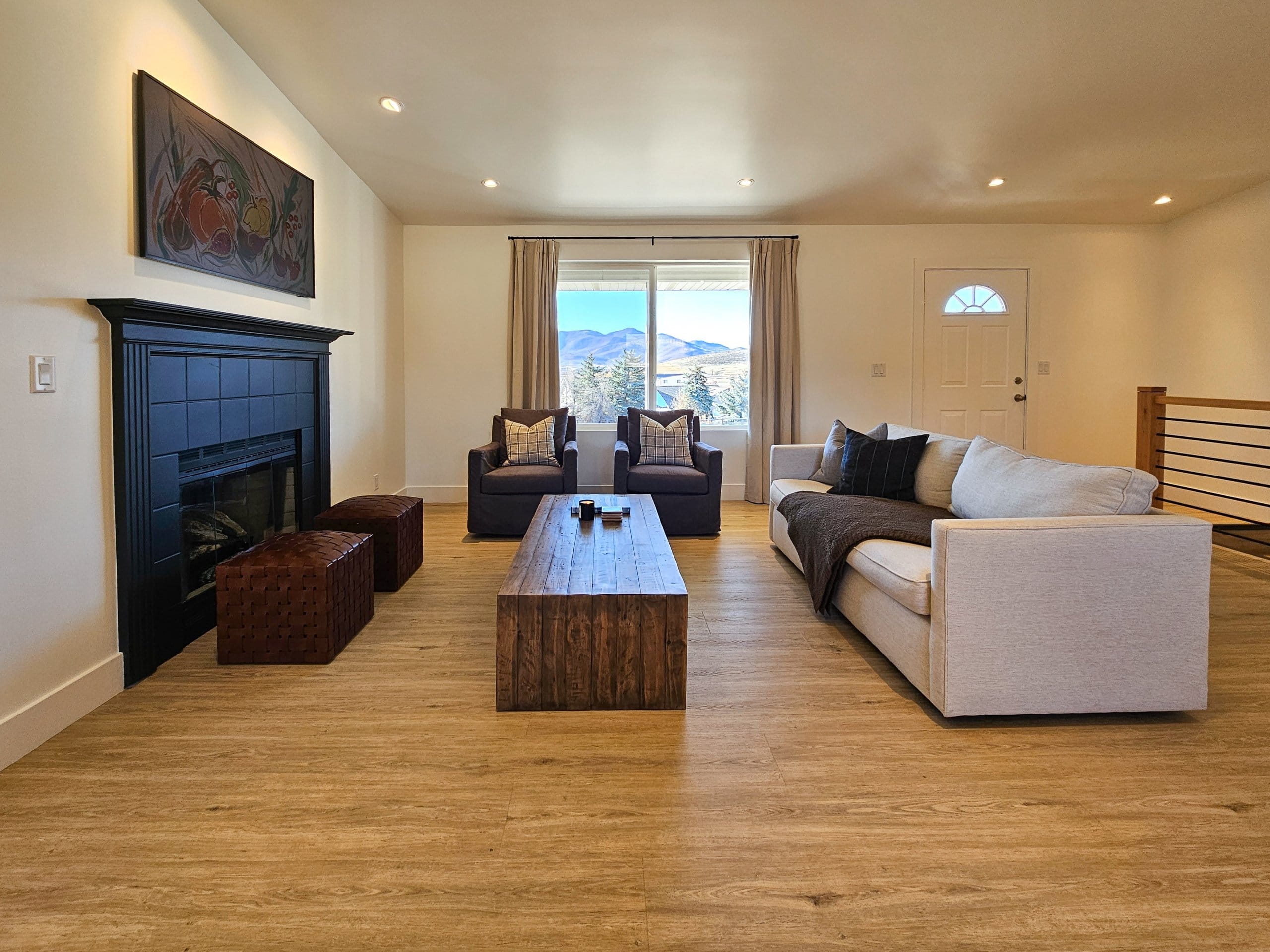 Family room with couch, ottomans, two chairs, and coffee table in front of the window and fireplace.
