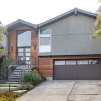 Thumbnail of http://Exterior%20of%20split%20level%20home%20after%20the%20renovation%20with%20a%20two-car%20garage,%20updated%20landscaping,%20and%20a%20modern%20railing%20leading%20up%20to%20the%20front%20porch%20and%20on%20the%20deck.