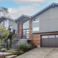 Thumbnail of http://Exterior%20of%20split%20level%20home%20after%20the%20renovation%20with%20a%20two-car%20garage,%20updated%20landscaping,%20and%20a%20modern%20railing%20leading%20up%20to%20the%20front%20porch%20and%20on%20the%20deck.