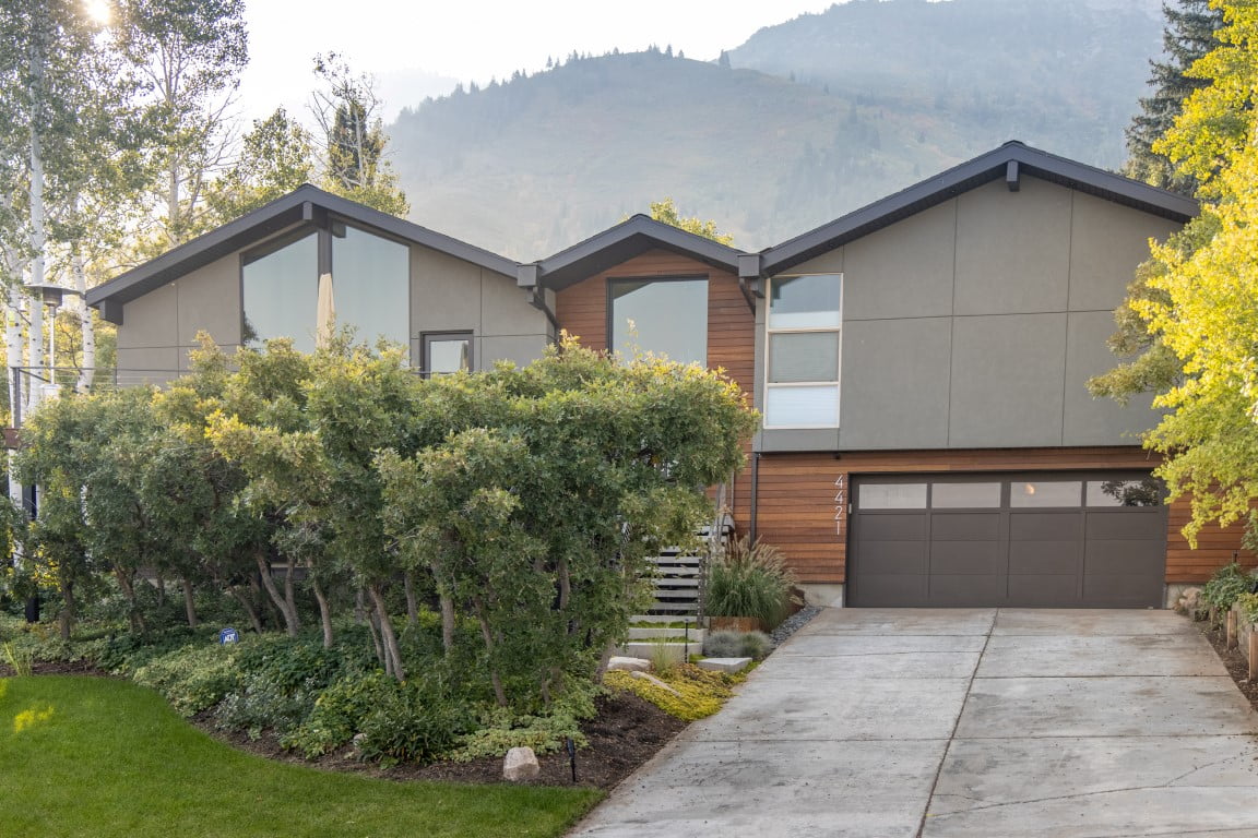 Exterior home renovation. The home sits in front of a beautiful mountain backdrop and is partially hidden by the landscaping.