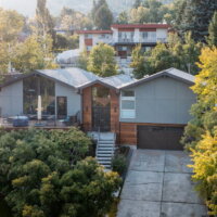 Thumbnail of http://Exterior%20of%20split%20level%20home%20after%20the%20renovation%20with%20a%20two-car%20garage,%20updated%20landscaping,%20and%20a%20modern%20railing%20leading%20up%20to%20the%20front%20porch%20and%20on%20the%20deck.%20The%20home%20sits%20in%20front%20of%20a%20beautiful%20mountain%20backdrop%20and%20is%20partially%20hidden%20by%20the%20landscaping.