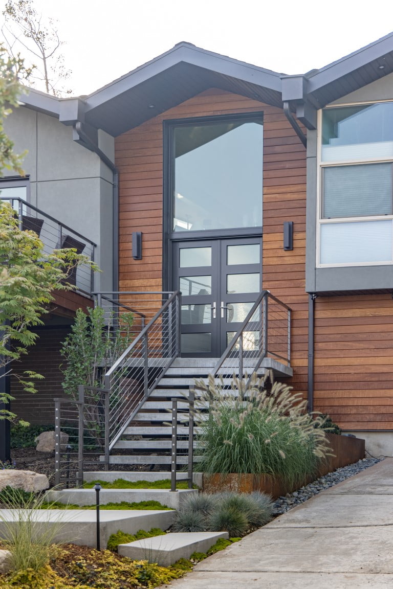 Exterior of split level home after the renovation with a modern front door and a railing up to the front porch.