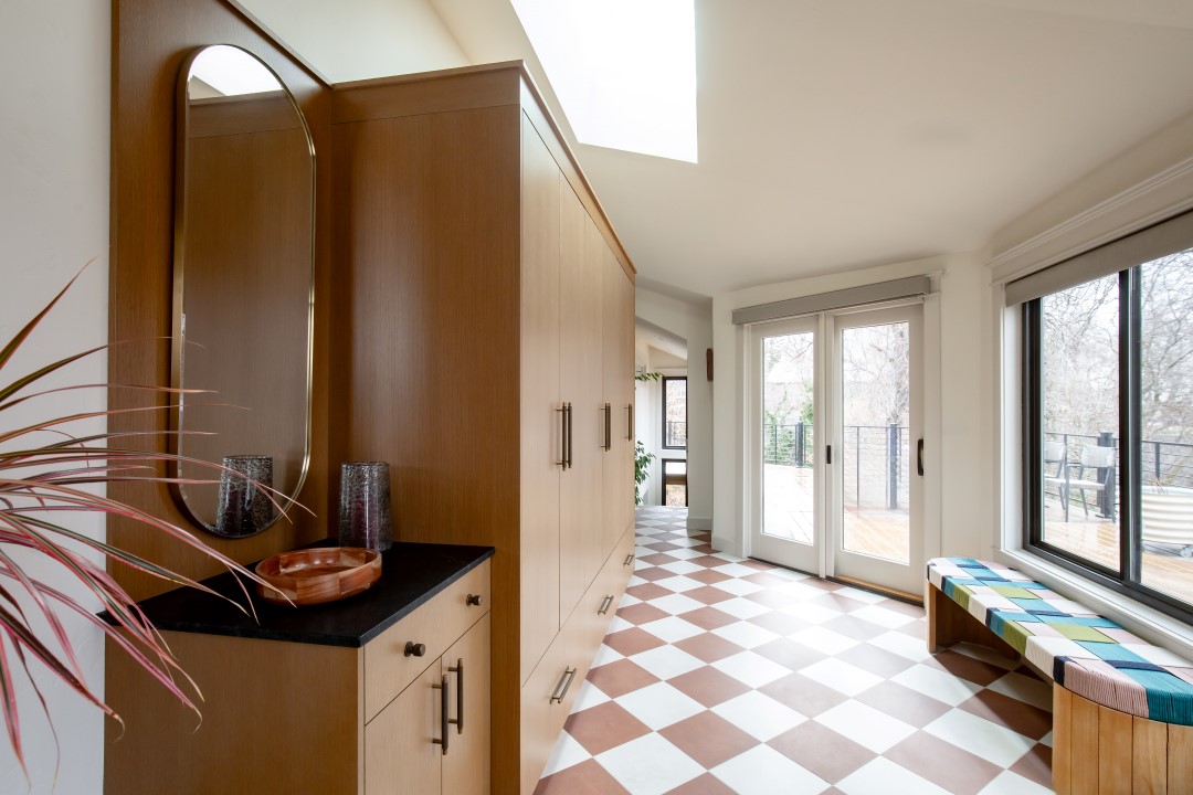 Mudroom after the remodel featuring a fun tile pattern on the floor, built-in cabinets, and lots of natural light