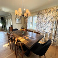 Thumbnail of http://Modern%20farmhouse%20dining%20room%20with%20a%20table%20under%20the%20light,%20floral%20curtains%20in%20front%20of%20the%20window,%20and%20seating%20for%20eight.