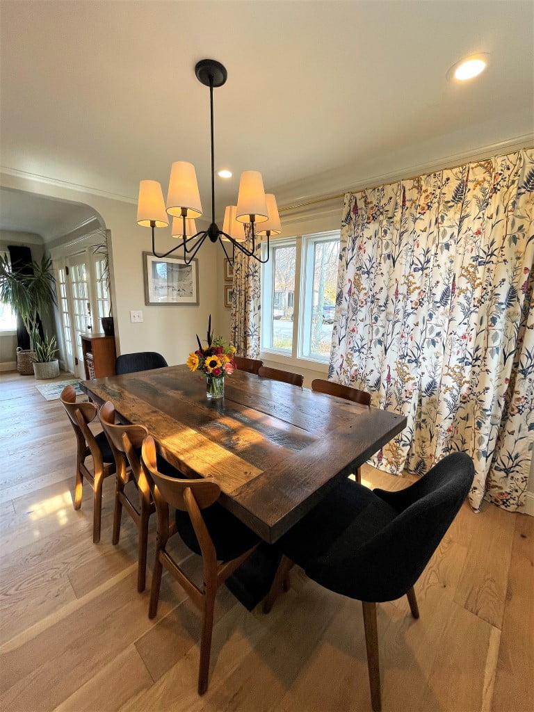 Modern farmhouse dining room with a table under the light, floral curtains in front of the window, and seating for eight.