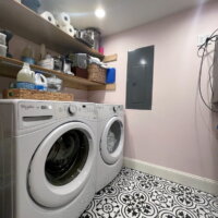 Thumbnail of http://Laundry%20room%20with%20a%20side-by-side%20washer%20and%20dryer%20and%20open%20shelves%20above.%20The%20floor%20is%20tile%20with%20a%20pattern,%20and%20the%20walls%20are%20painted%20pink.