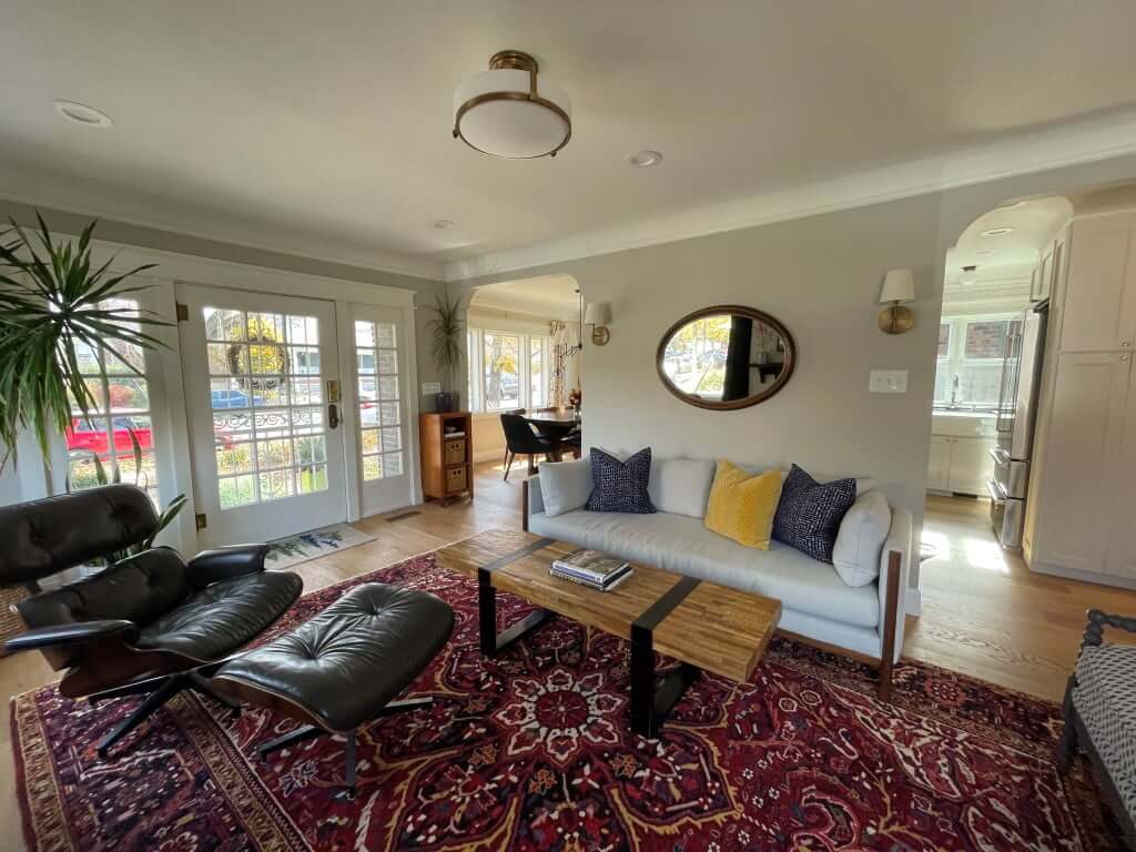 Renovated living room and entry area. The living room includes two arched openings with access to the dining room and kitchen. Between the openings is the couch.