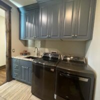 Thumbnail of http://Laundry%20room%20with%20side-by-side%20washer%20and%20dryer,%20blue%20painted%20cabinets,%20and%20a%20sink%20with%20a%20small%20area%20rug%20on%20the%20floor%20in%20front.