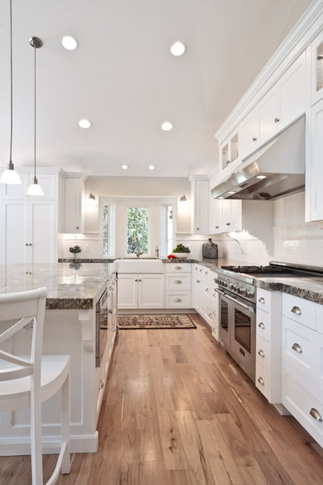 Large Kitchen with white cabinets and hardwood floors and farm sink | Renovation Design Group