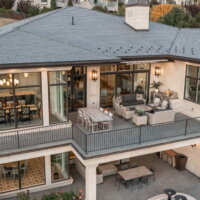 Thumbnail of http://Exterior%20of%20a%20house%20with%20a%20covered%20patio%20under%20the%20deck.%20Both%20spaces%20include%20outdoor%20furniture%20and%20windows%20with%20views%20to%20the%20interior%20of%20the%20home.