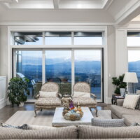 Thumbnail of http://Living%20room%20with%20large%20windows%20and%20doors%20out%20to%20the%20deck%20and%20furniture%20in%20front%20of%20the%20fireplace.