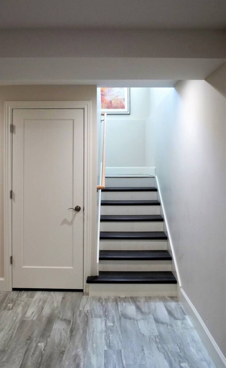 Hallway with stairs on the right and a door on the left.