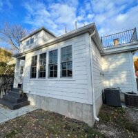 Thumbnail of http://Exterior%20of%20a%20home%20addition.%20The%20addition%20includes%20white%20side%20paneling,%20stairs%20from%20a%20back%20porch,%20and%20a%20railing%20above.