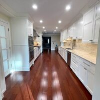 Thumbnail of http://Long%20Traditional%20kitchen%20renovation%20with%20white%20cabinetry%20and%20wood%20flooring.