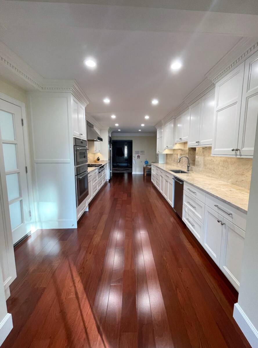 Long Traditional kitchen renovation with white cabinetry and wood flooring.