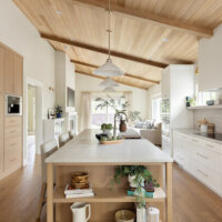 Thumbnail of http://Open%20concept%20kitchen%20with%20a%20large%20island%20in%20the%20center.%20On%20the%20right%20is%20a%20wall%20of%20cabinetry%20that%20includes%20the%20oven,%20stove,%20and%20fridge.%20In%20the%20center%20is%20a%20large%20island%20with%20open%20shelves%20on%20the%20end%20,%20the%20sink,%20and%20seating.%20On%20the%20left%20is%20a%20additional%20cabinetry%20with%20a%20built-in%20coffee%20machine.