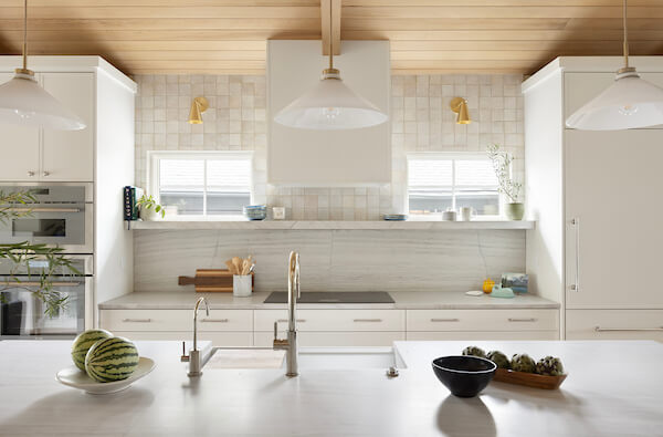 New kitchen design with white cabinetry, gold fixtures, and wood on the partially vaulted ceiling.