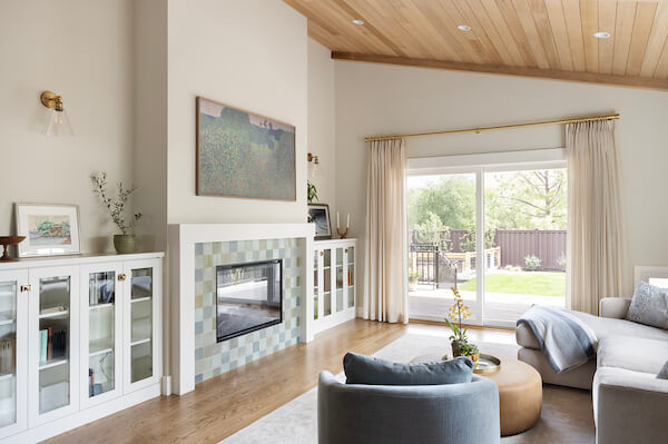 Living room with a vaulted ceiling, fireplace framed by bookcases, and an open concept layout to the kitchen and dining room.
