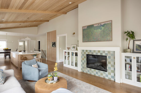 Living room with a vaulted ceiling, fireplace framed by bookcases, and an open concept layout to the kitchen and dining room.