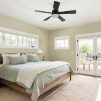 Thumbnail of http://Primary%20bedroom%20with%20multiple%20windows,%20including%20two%20doors%20out%20to%20the%20back%20deck.%20The%20room%20is%20furnished%20with%20a%20bed,%20rug,%20and%20two%20nightstands.
