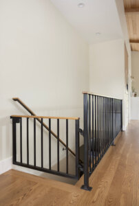 Custom built-in dog gate at the top of the stairs that matches with the railing. Dog-friendly home design ideas.