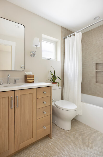 Basement bathroom with a simple design. Includes a vanity with storage, toilet, and combined shower and tub.