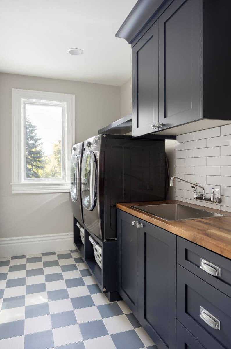 Laundry room with the washer and dryer raised up on a cabinet and a sink adjacent.