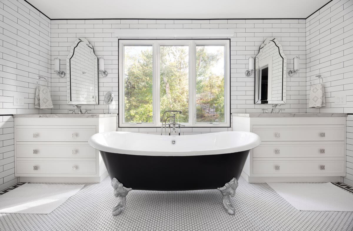 Large claw foot tub with a window centered above and a vanity on either side.